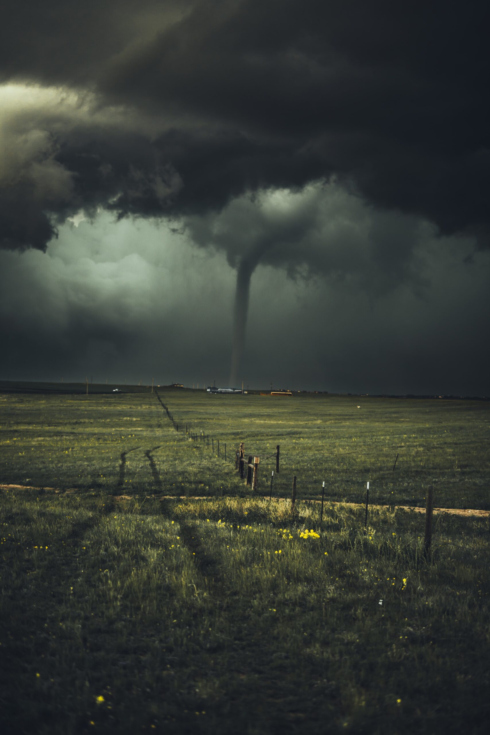 A stormy sky with a tornado forming in a large field